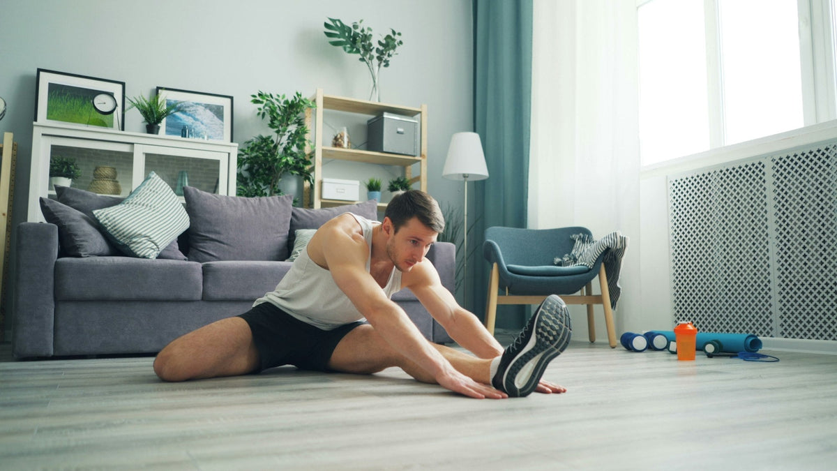 Man stretching his hamstrings on a mat in his living room