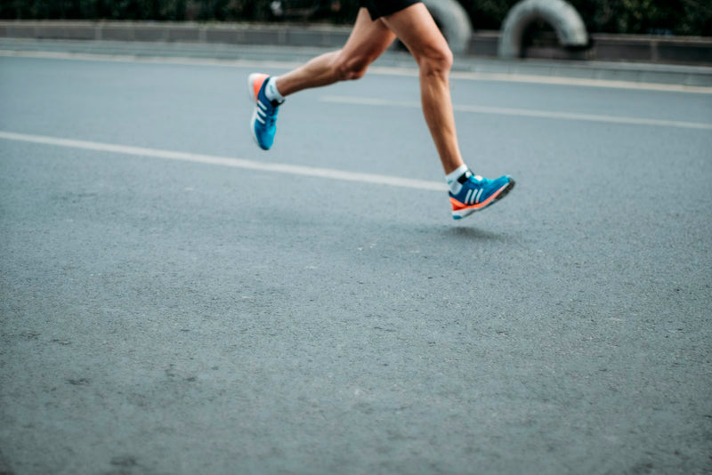 Close-up of a runner's legs mid-stride on the road
