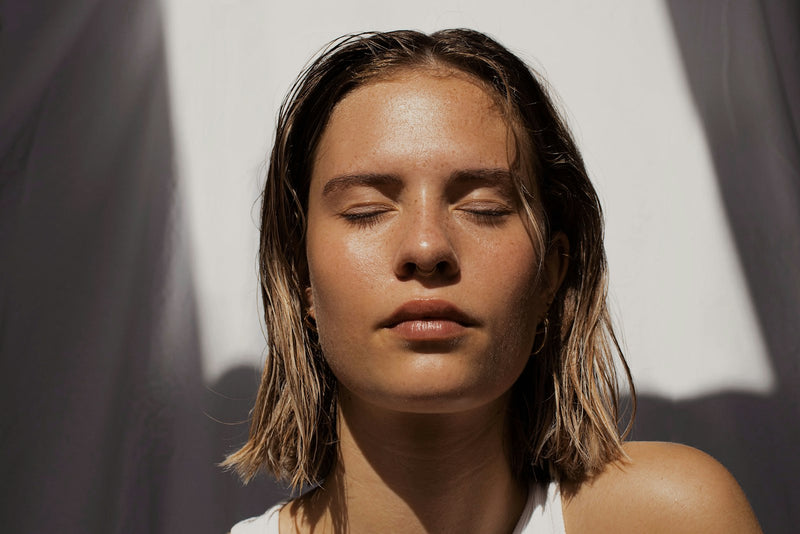 Woman with clear, glowing skin and eyes closed